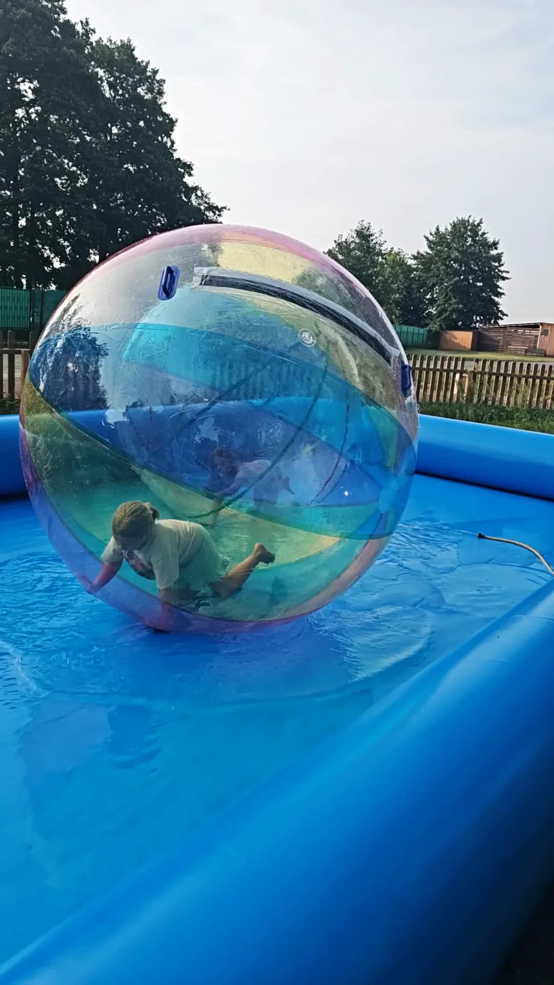 Dziecko w kuli wodnej na niebieskim basenie w słoneczny dzień