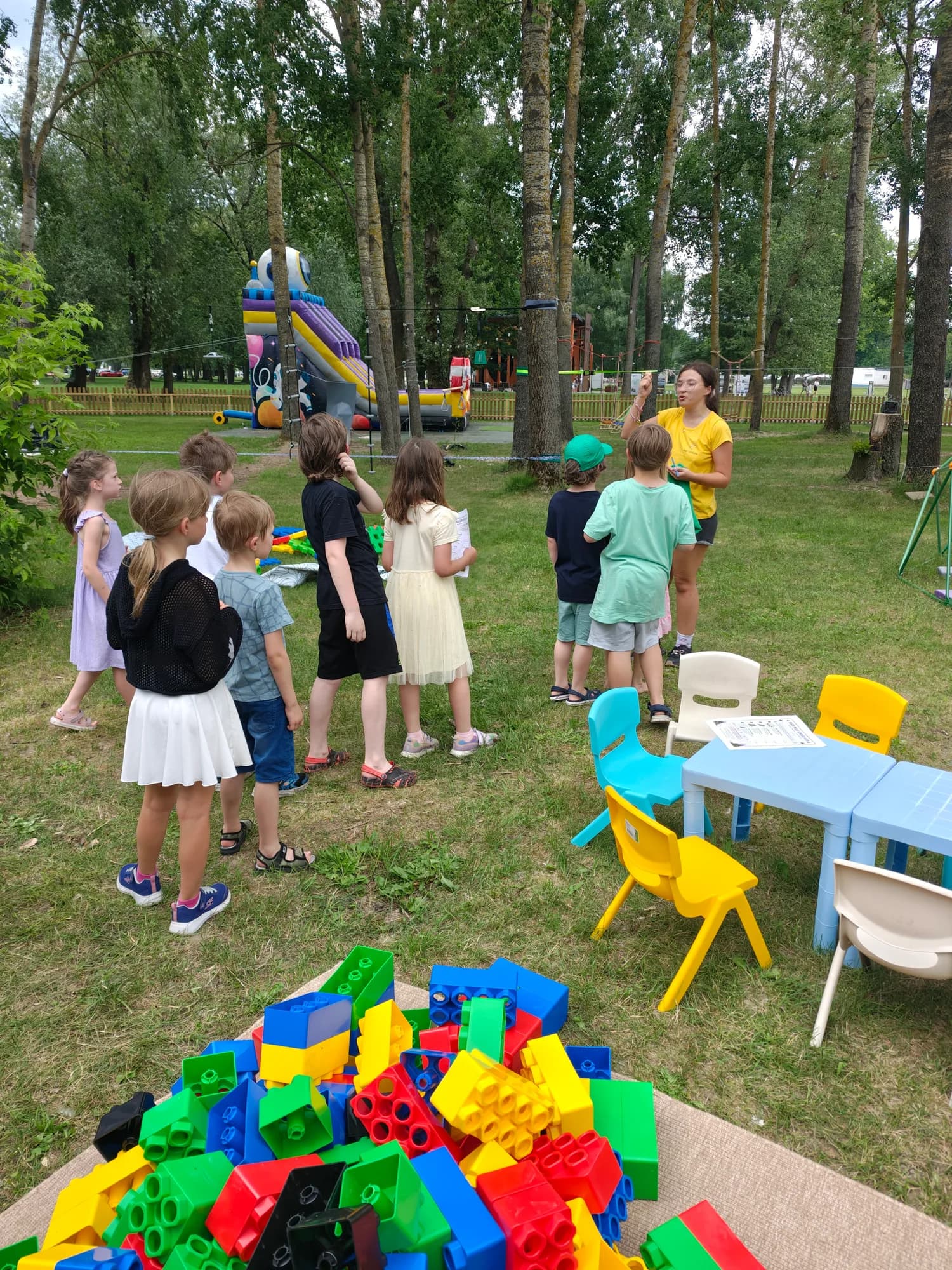 Dzieci budują z wielkich kolorowych klocków na trawie