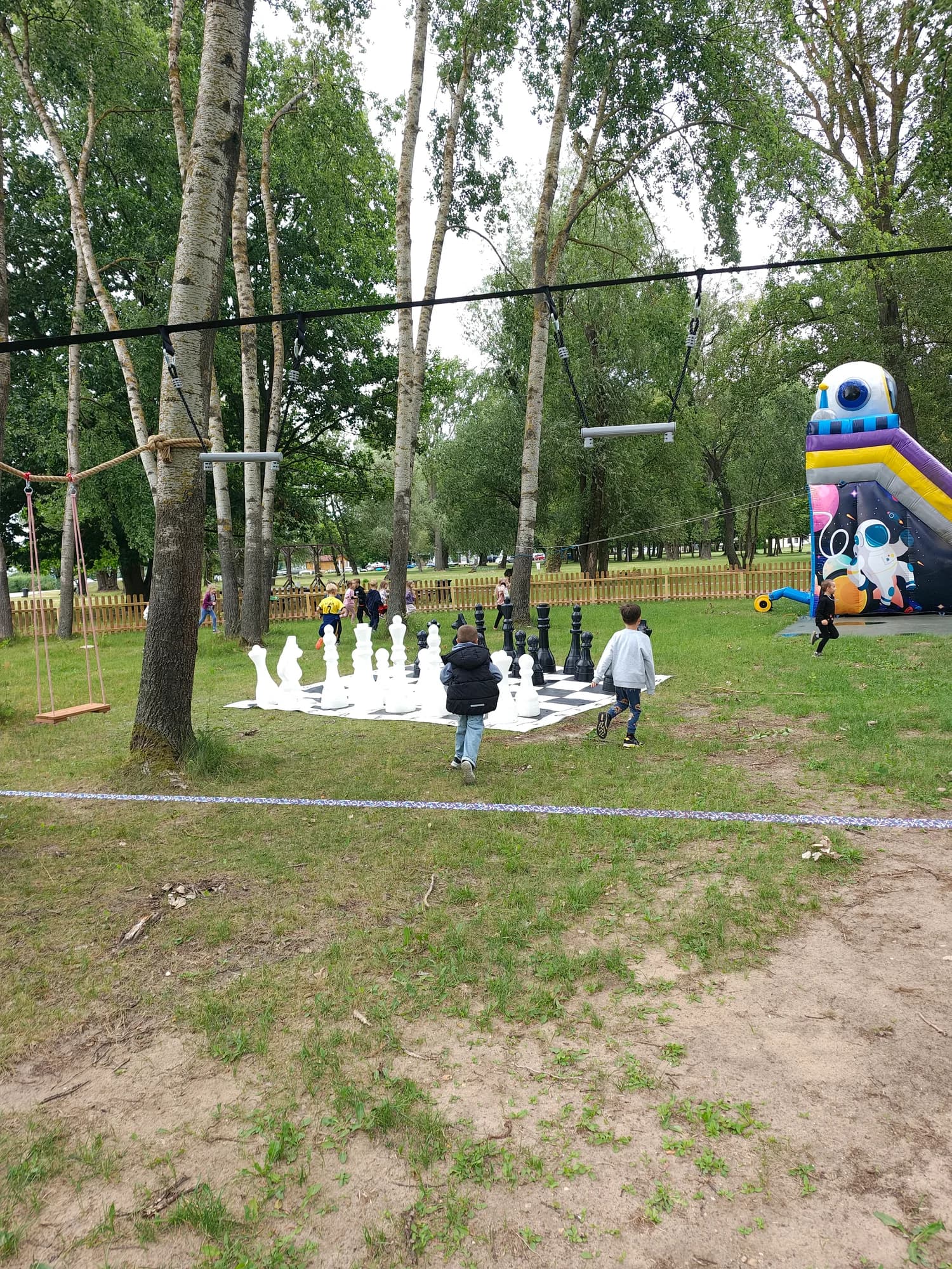 Ogrodowe szachy XXL i dmuchaniec na polanie w tle